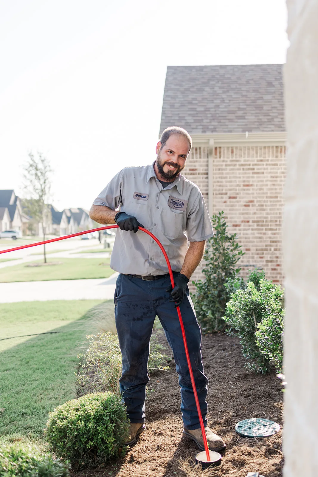 Plumber feeding a sewer inspection cable into a cleanout at a North Texas home